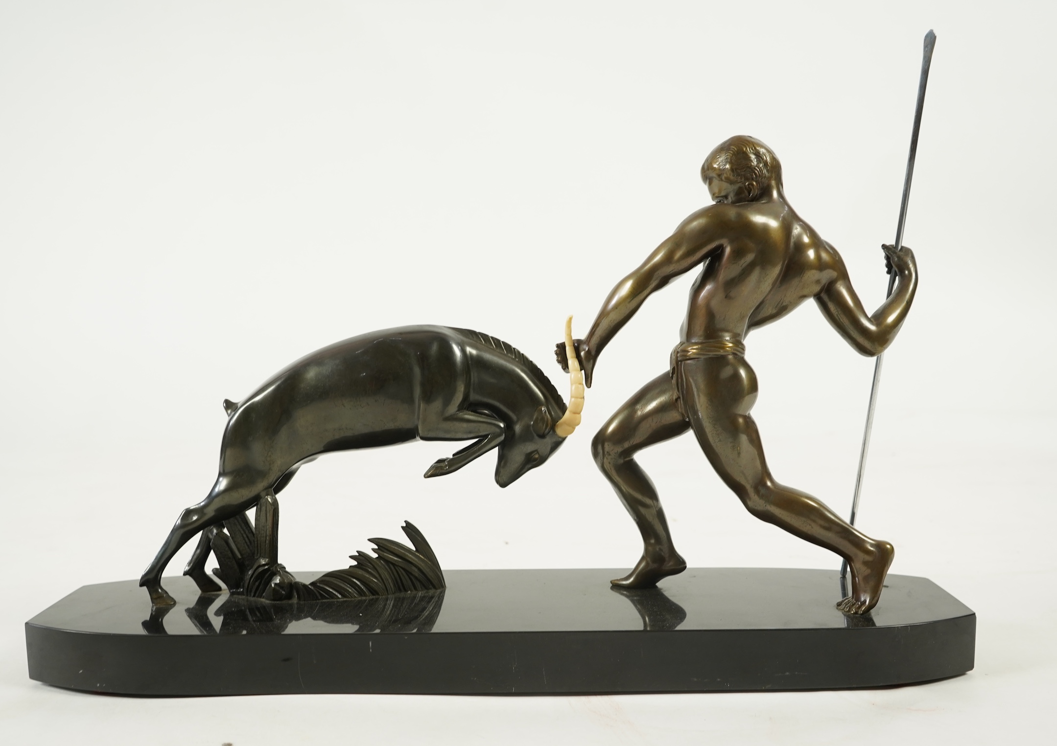 Attributed to Zoltan Kovasz (Romanian, 1883-1952), a bronzed spelter male hunter holding a chromed spear, with springbok, on a polished slate base